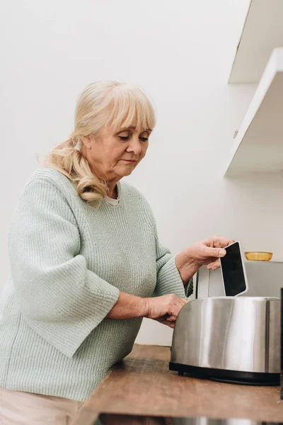 Συνταξιούχος Γυναίκα Άνοια Νόσου Βάζοντας Smartphone Τοστιέρα — Φωτογραφία Αρχείου