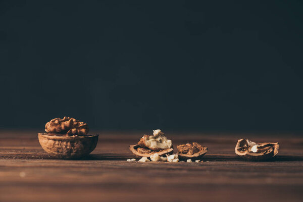 треснувшие грецкие орехи как символ слабоумия на деревянном столе на черном фоне
 