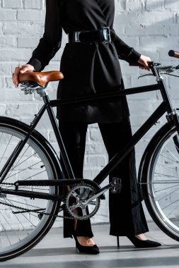woman in black clothes holding black bike  clipart