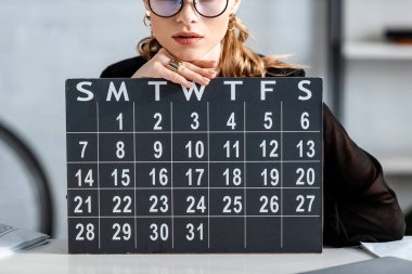 businesswoman in black clothes and glasses holding calendar  clipart