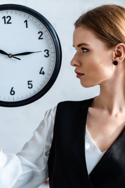 saat tutan ve uzağa bakarak formal giyim güzel odaklı kadın