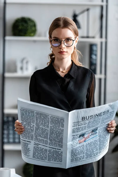 Attraktiva Affärskvinna Svarta Kläder Och Glasögon Håller Tidningen Och Tittar — Stockfoto