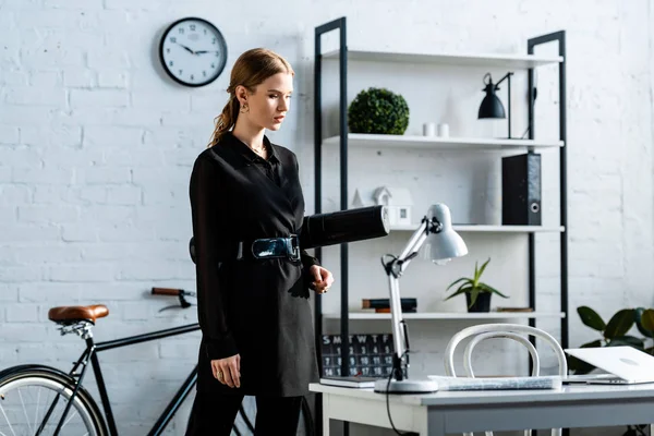 事務所に立っていると紙管を保持している黒い服を着た美しい女性実業家 — ストック写真