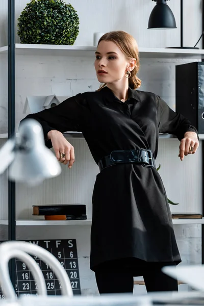 よそ見の職場で黒のフォーマルな服装でスタイリッシュな女性 — ストック写真