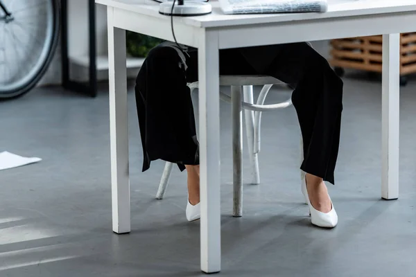 Cropped View Woman White Shoes Trousers Sitting Table Workplace — Stock Photo, Image