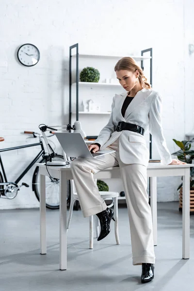时尚的女商人在白色正式穿坐在办公桌上 并在工作场所使用笔记本电脑 — 图库照片