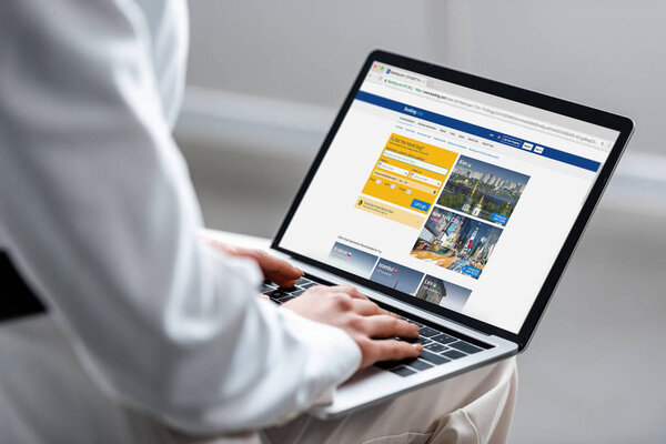 обрезанный вид женщины с помощью ноутбука с бронированием веб-сайт на экране
