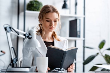 masada oturan ve gönüllülük defter işyerinde formal giyim içinde ciddi iş kadını