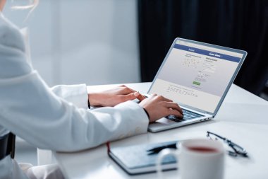 facebook Web sitesinde ofis masası ekranında ile dizüstü bilgisayar kullanan kadın kırpılmış görünümünü
