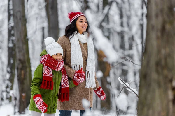 有吸引力的非洲裔美国母亲和学龄前女儿微笑着走在冬季公园 — 图库照片