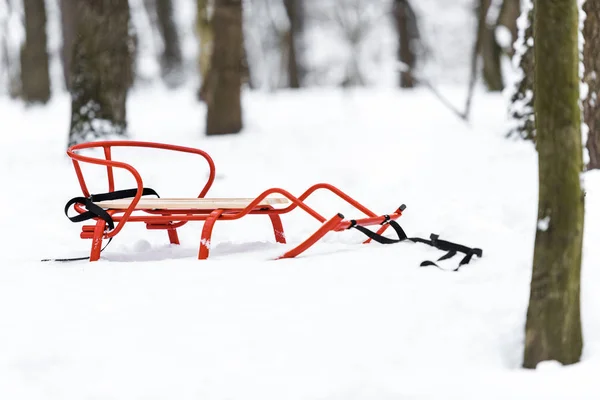 冬の公園で雪に赤い金属そり — ストック写真