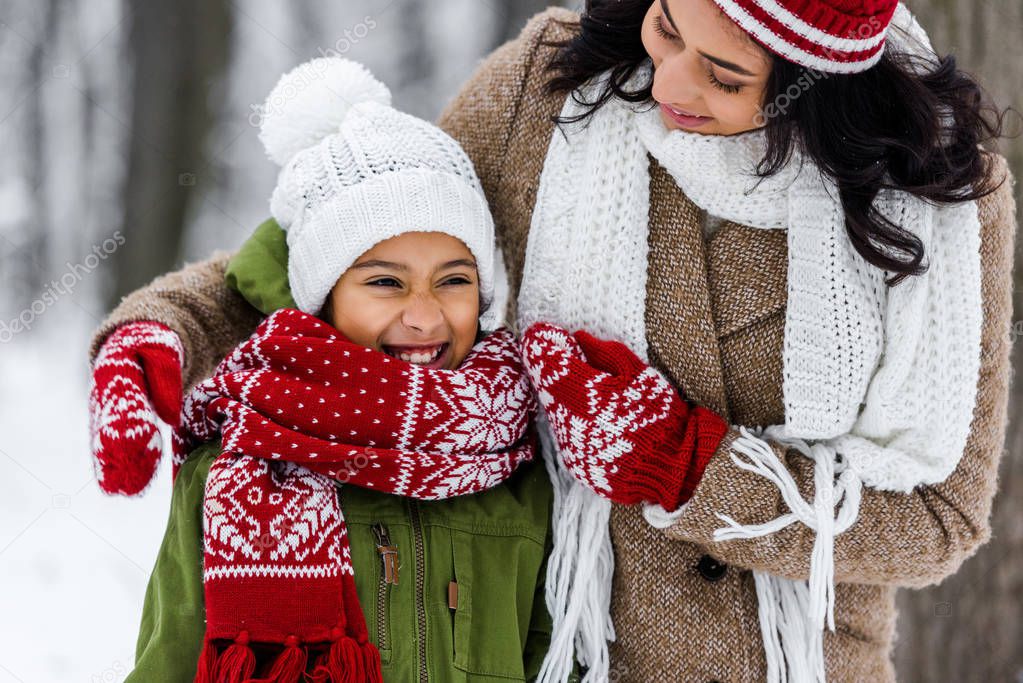 attractive african american woman looking at smiling preteen daughter in winter park