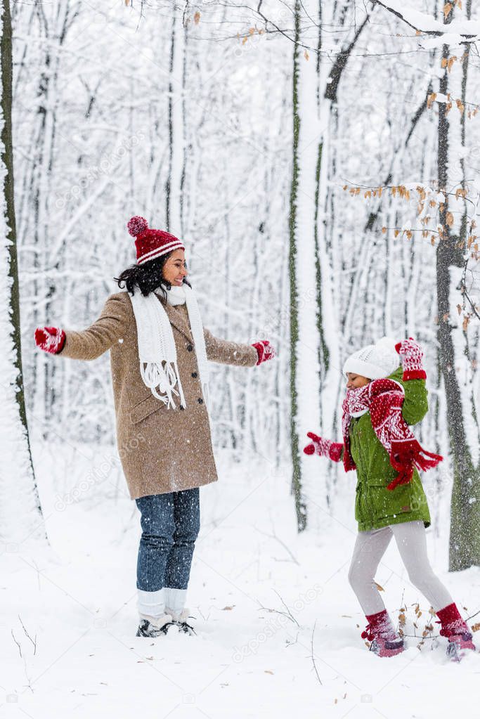cheerful african american woman and preteen daughter having fun in winter park