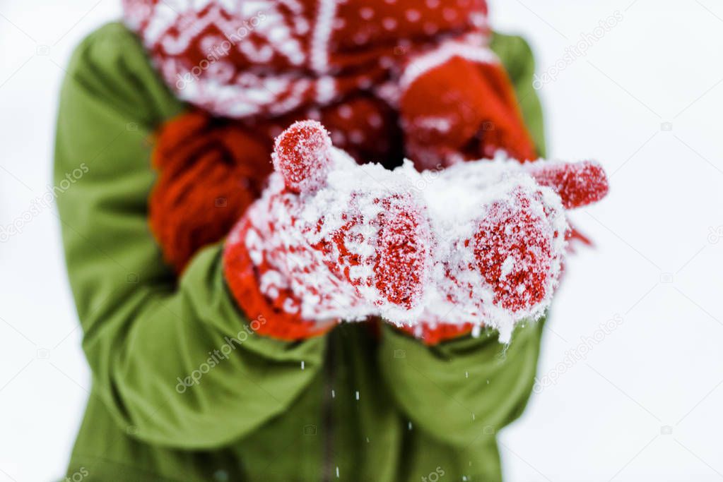 child with red gloves blowing white snow 