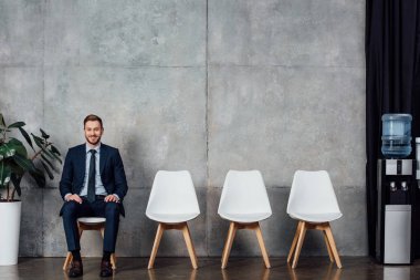 bekleyen salonda oturmuş ve kameraya bakarak elbiseli şık iş adamı