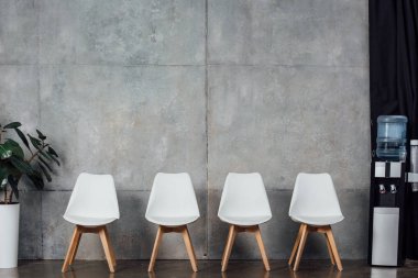 bekleme salonunda bitki ve su soğutucu ile modern beyaz sandalye