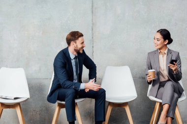 yakışıklı işadamı kahve ve smartphone bekleme salonunda Asya işkadını konuşuyor