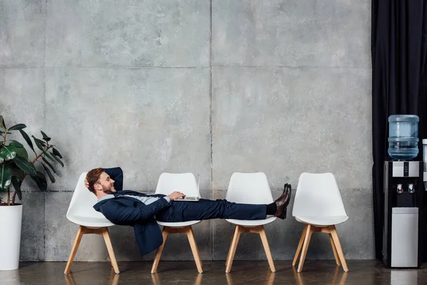 Homem Negócios Sorridente Deitado Cadeiras Usando Laptop Sala Espera — Fotografia de Stock