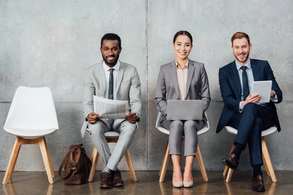 Sonrientes Empresarios Multiétnicos Leyendo Periódicos Utilizando Dispositivos Digitales Sala Espera — Foto de Stock