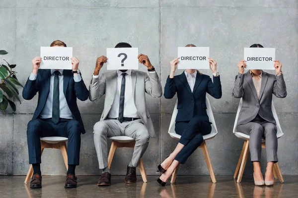 Empresários Multiétnicos Sentados Segurando Cartões Com Palavras Diretor Ponto Interrogação — Fotografia de Stock