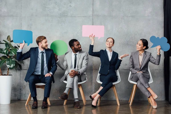 Smiling Multiethnic Businesspeople Holding Speech Bubbles Thought Bubble While Sitting — Stock Photo, Image