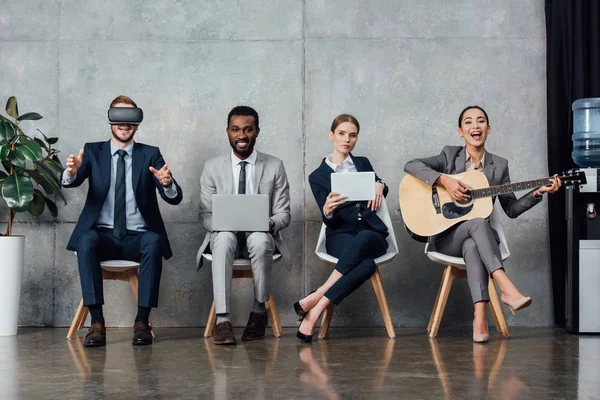 Empresarios Multiétnicos Sentados Sillas Utilizando Dispositivos Digitales Tocando Guitarra Acústica — Foto de Stock