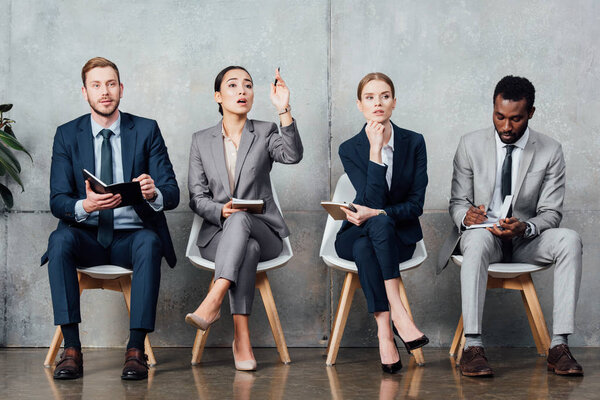asian businesswoman raising hand while having meeting with multiethnic colleagues in office