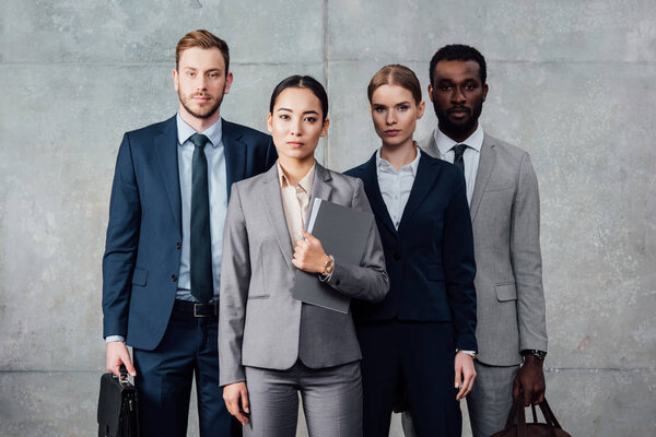 focused multiethnic group of businesspeople in formal wear posing and looking at camera 