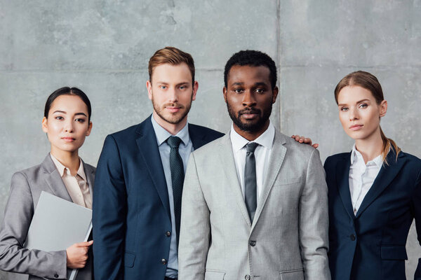 serious multiethnic group of businesspeople in formal wear posing and looking at camera
