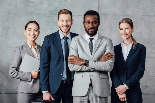 happy multiethnic group of businesspeople in formal wear posing and looking at camera