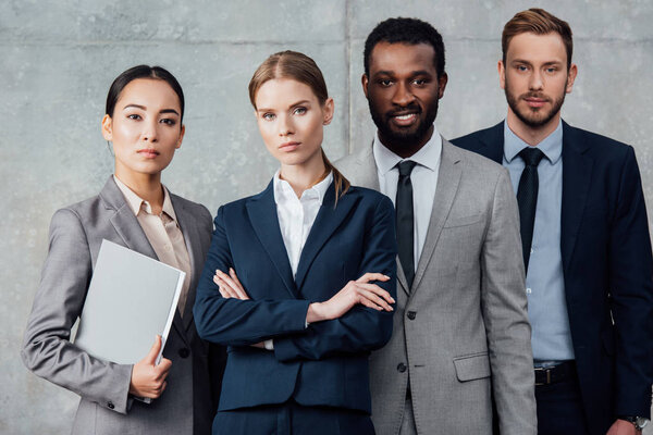 focused multiethnic group of businesspeople in formal wear posing and looking at camera