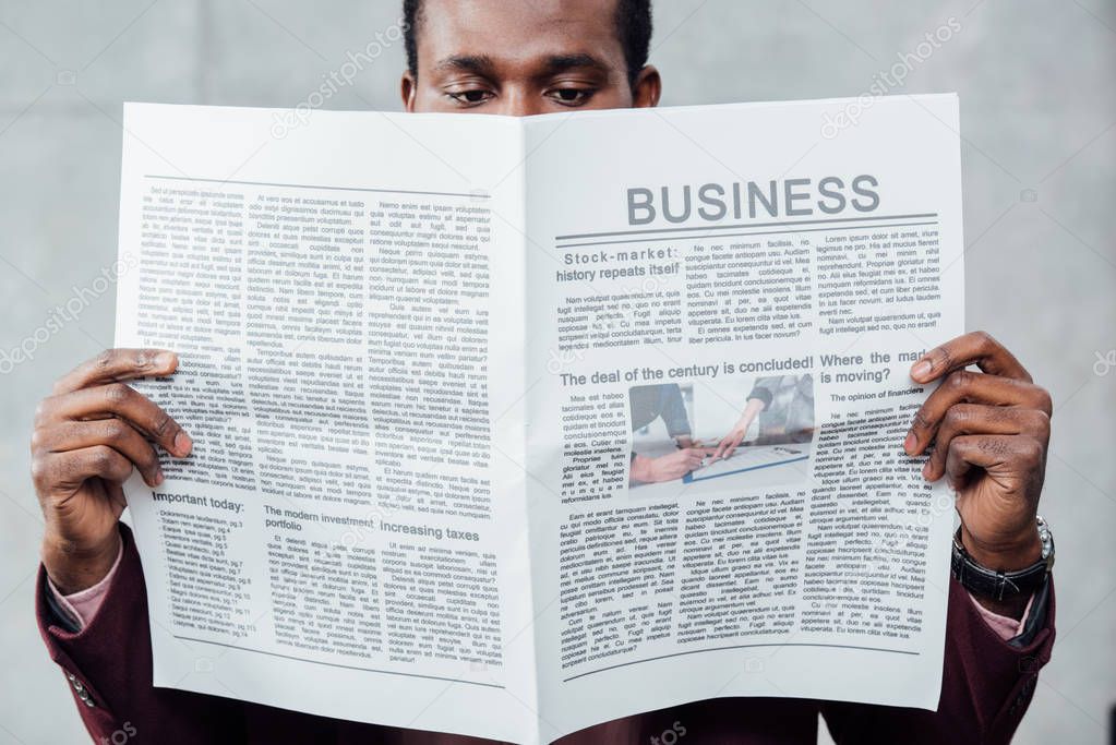 focused african american casual businessman reading newspaper