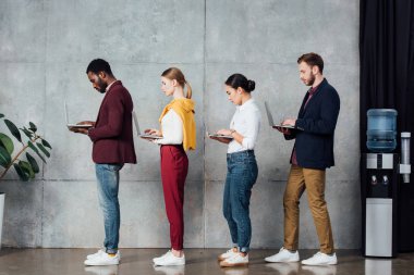 bekleme salonunda dizüstü bilgisayarlar kullanarak çok ırklı rahat iş adamları