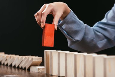 cropped view of woman picking red wooden brick from row of blocks isolated on black clipart