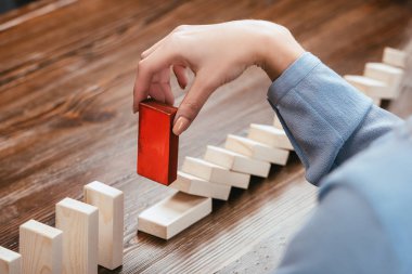 cropped view of woman picking red wooden brick from row of blocks