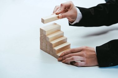 cropped view of woman putting wooden brick on top of wooden blocks symbolizing career ladder