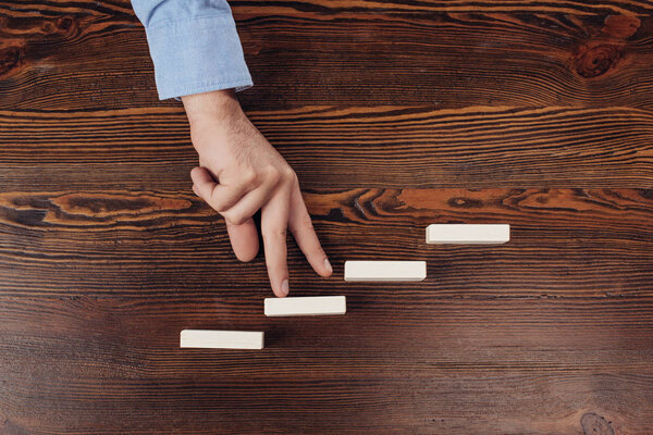 cropped view of man walking with fingers on wooden blocks symbolizing career ladder 