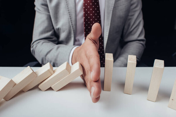 close up view of businessman preventing wooden blocks from falling