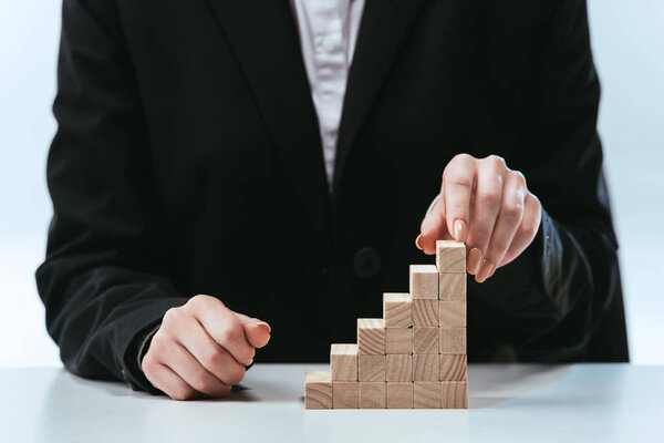 cropped view of woman with wooden blocks symbolizing career ladder