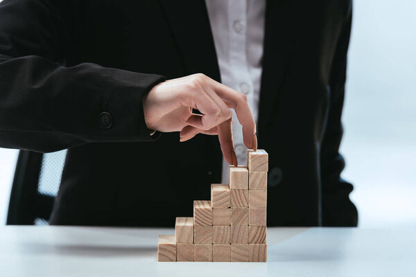 cropped view of woman walking with fingers on wooden blocks symbolizing career ladder