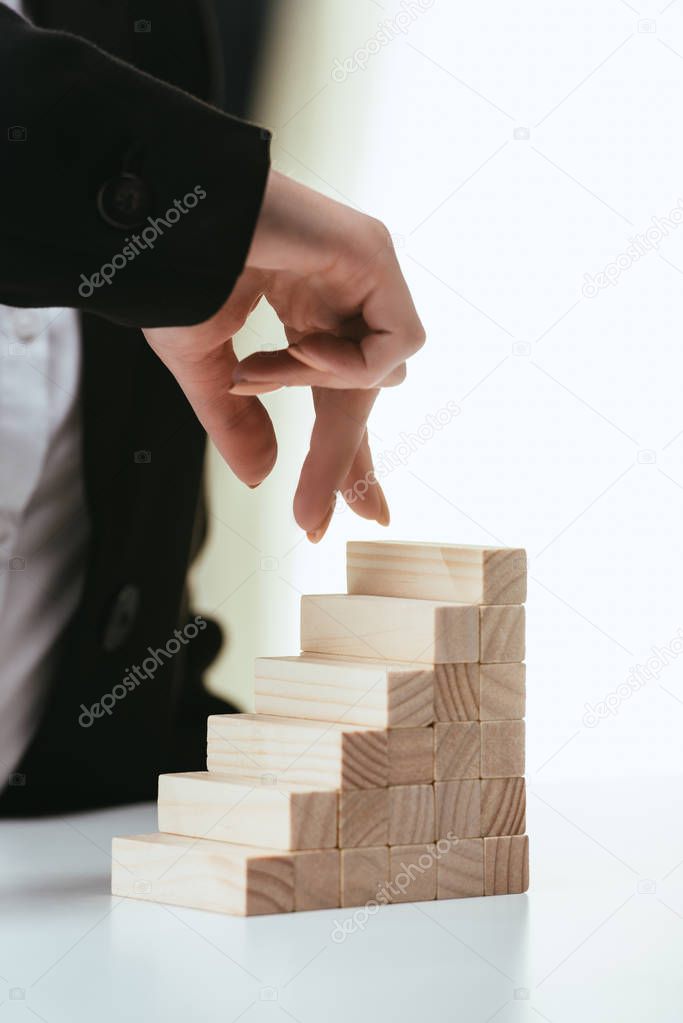 partial view of woman walking with fingers on wooden blocks symbolizing career ladder