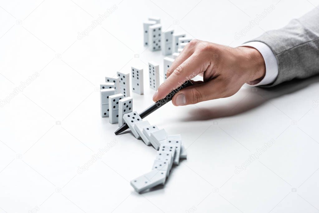 cropped view of man preventing dominoes from falling with pen on white background