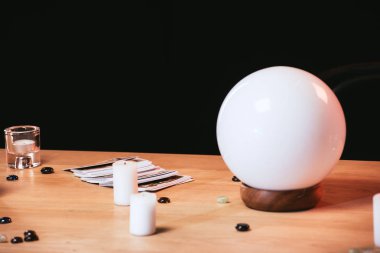 selective focus of fortune teller near candles on wooden table isolated on black  clipart