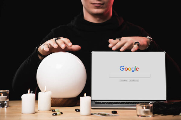 cropped view of psychic near laptop with google website on screen isolated on black 