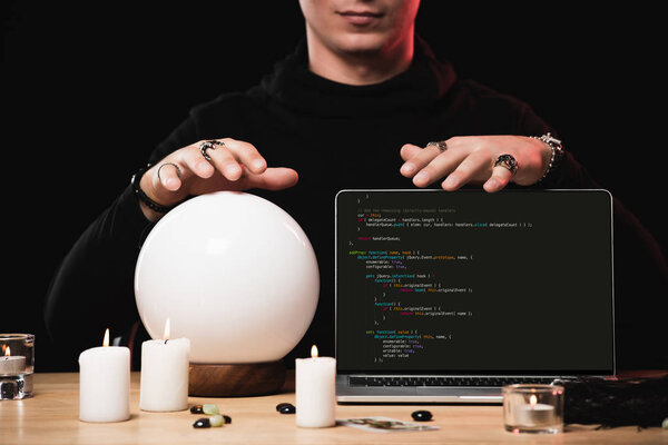 cropped view of psychic near laptop with programming code on screen isolated on black 