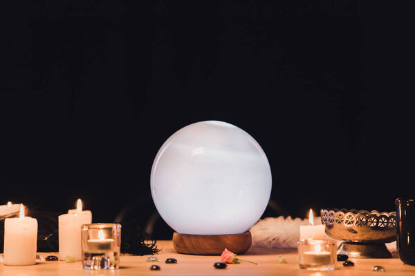 selective focus of fortune teller near candles on wooden table isolated on black 