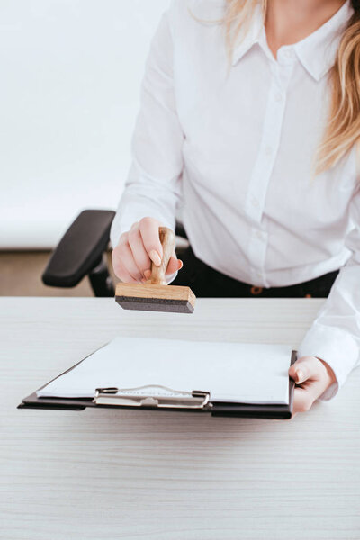 selective focus of  female lawyer holding clipboard and stamp in hands