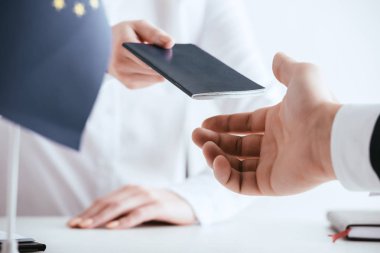 cropped view of travel agent giving passport to tourist isolated on white