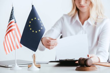 Kırpılan görünümü belge üzerinde beyaz izole Amerikan ve Avrupa bayrakları yakınındaki tutan kadın