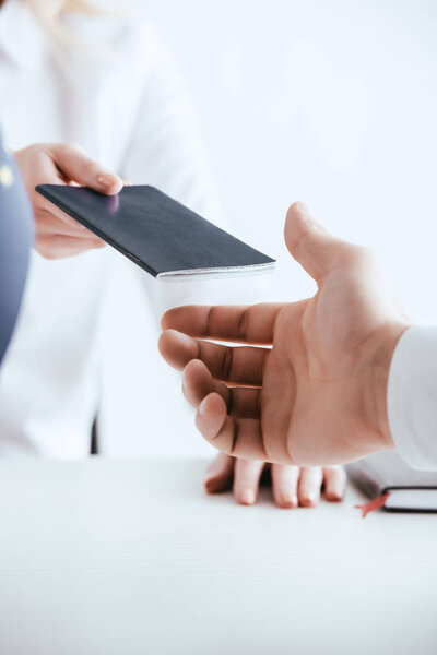selective focus of woman giving passport to tourist isolated on white